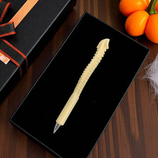 Decorative pen with textured design on a black tray, surrounded by Halloween-themed items.