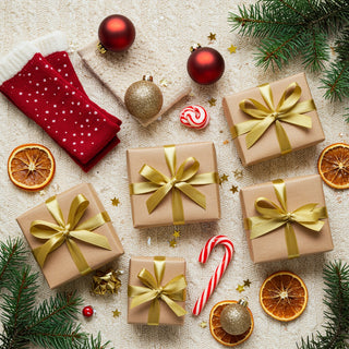 Christmas-themed arrangement with gift boxes, ribbons, and festive decorations on a textured surface.