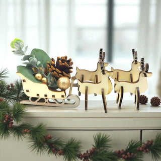 Decorative set with wooden reindeer and a sleigh on a white surface with greenery.