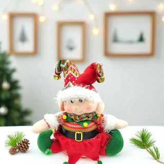 Decorative elf plush toy with festive attire on a white surface with Christmas decorations in the background.