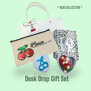 Desk drop gift set with pouch, small bag, and decorative items on a light green background