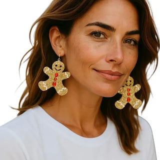 Woman wearing gold gingerbread man earrings on a white background