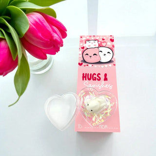 Heart-shaped product with 'Hugs & Kisses' packaging next to pink tulips on a white background