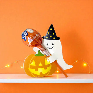 Halloween-themed decoration with a ghost, pumpkin, and lollipop on an orange background