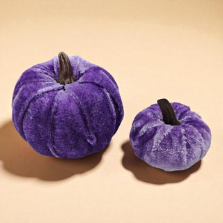 Two purple velvet pumpkins on a beige background