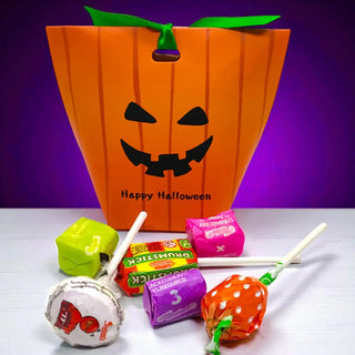 Halloween-themed candy bag with lollipops and small boxes on a white surface against a purple background