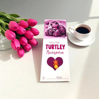 Greeting card with turtle illustration, pink tulips, and coffee on a white surface