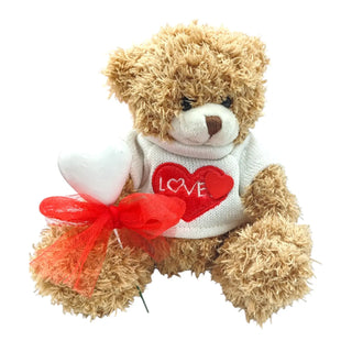 Teddy bear wearing a sweater with a heart and 'LOVE' text, holding a red bow, on a white background