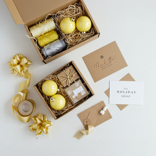 Decorative gift set with yellow ornaments, ribbons, and cards on a white background.