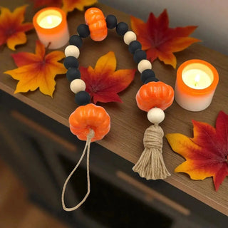Decorative beaded string with pumpkins and a tassel,  on a wooden background.