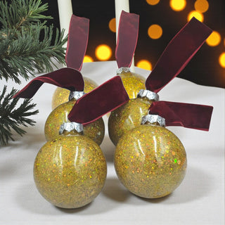 Gold glittery Christmas ball ornament with a red ribbon, showing measurements on a white background.