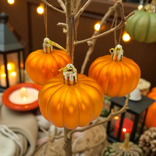 Decorative pumpkins on a branch with candles and lanterns in the background