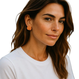 Woman wearing orange earrings with a plain background