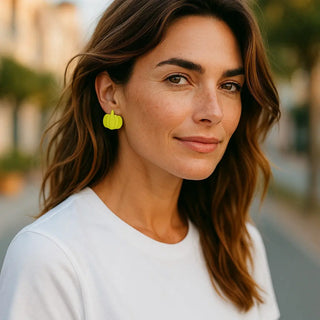 Woman wearing yellow earrings with a blurred outdoor background
