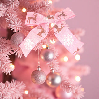 Decorative pink bow with reindeer designs on a Christmas tree with pink ornaments.
