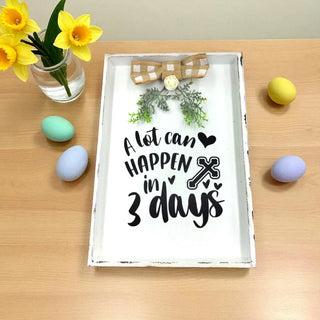 Decorative tray with a motivational quote on a wooden surface with Easter eggs and flowers.