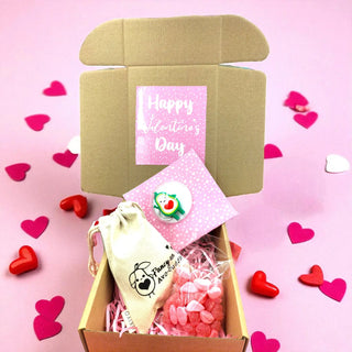 Valentine's Day gift box with heart-shaped confetti on a pink background