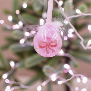 Pink Christmas ornament with a bow on a Christmas tree with lights for a Ballet Nutcracker theme