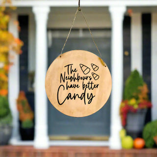 Wooden sign with text hanging on a door, with a blurred outdoor background.