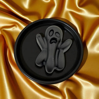 Black ghost-shaped mold on a gold satin background