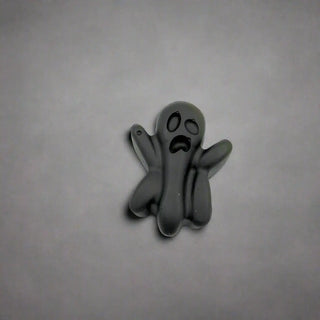 Black ghost-shaped decorative item on a white napkin with Halloween-themed background