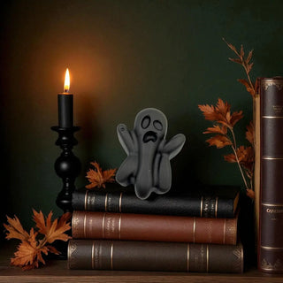 Stack of books with a candle and ghost figurine on a dark background