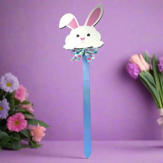 White bunny-shaped wand with pink ears and a blue handle on a white background