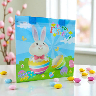 Colorful Easter card with a cartoon bunny and 'Happy Easter!' text, surrounded by Easter eggs on a table.