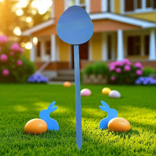 Decorative Easter egg and bunny figures on grass with a house in the background