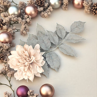 Decorative arrangement with flowers, leaves, and metallic ornaments on a light background