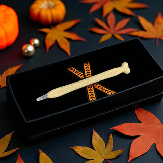 Decorative pen with decorative elements on a dark surface with autumn leaves.