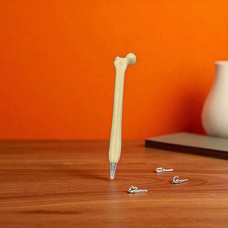 Pen with bone-shaped handle on a wooden surface against an orange wall