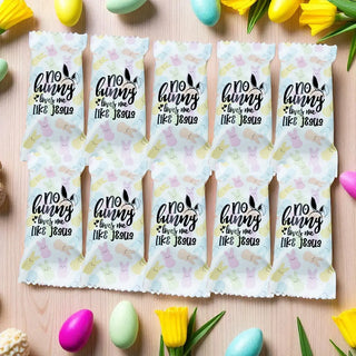 Packets with 'no bunny loves me like Jesus' text on a wooden surface with Easter eggs and flowers.