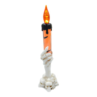 Halloween decorative candle with skeleton hand holding it on a white background