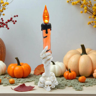 Halloween-themed candle with a skeleton hand holder, surrounded by pumpkins and autumn decorations.