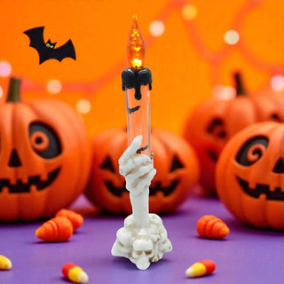 Halloween-themed candle with a skeleton hand and jack-o'-lanterns in the background