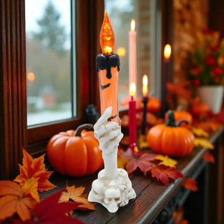 Halloween-themed candle holder with a candle on a windowsill with pumpkins and leaves.
