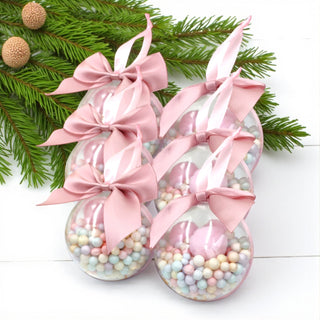 Decorativeballs with pink bows and pastel beads on a white background with greenery.