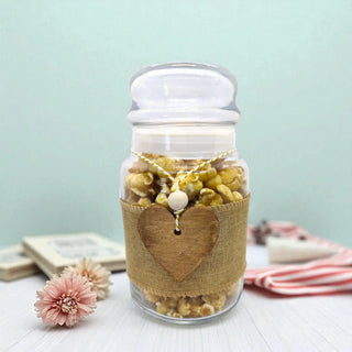 Jar of popcorn with a heart-shaped label on a light blue background
