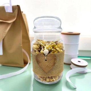 Jar of popcorn with a heart-shaped label on a light green surface