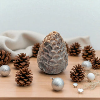 Decorative arrangement of pine cones and silver ornaments on a wooden surface with a neutral background.