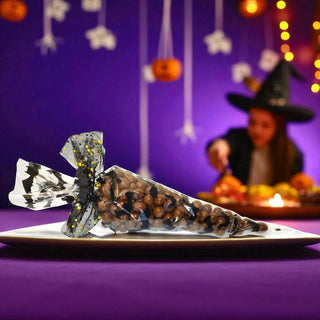 Halloween-themed candy on a plate with a blurred witch figure and decorations in the background.