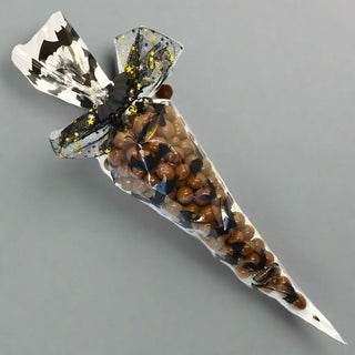 Halloween-themed candy cone with decorative paper on a wooden surface with pumpkins.