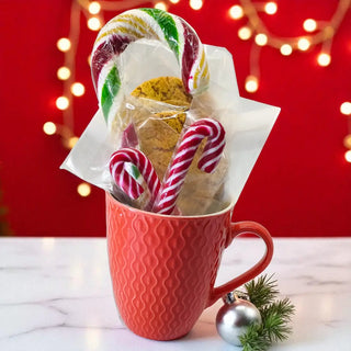Red mug with cookies and candy canes against a festive background