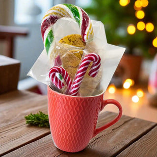 Pink mug with cookies and candy canes on a wooden table