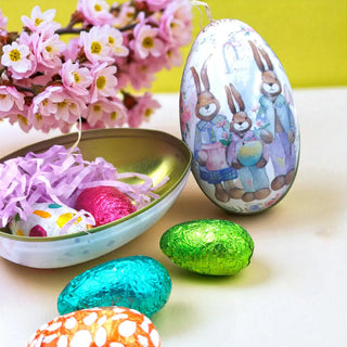 Decorative Easter egg with rabbit design, surrounded by other Easter eggs and a bowl of candy on a yellow background.