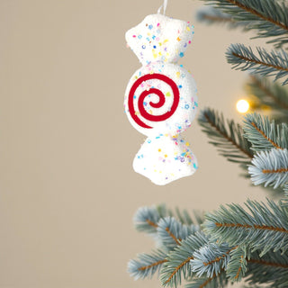 Confetti nougat candy ornament on frosted pine tree with warm fairy lights. Pastel Candyland Christmas decorating inspiration.