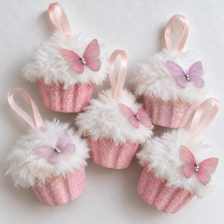 Five pink glitter cupcake ornaments with fluffy white faux-fur tops, pastel pink ribbon loops, and pink-and-purple butterfly decorations, arranged on a white background.