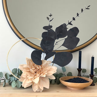 Decorative setup with flowers, leaves, and a mirror on a surface.