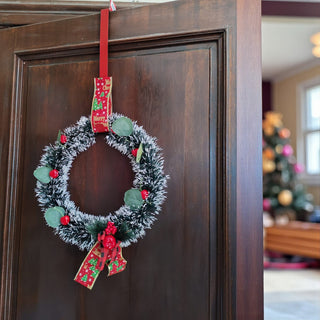 Christmas wreath with red ribbons hanging on a wooden door